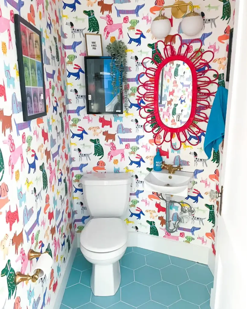 Small powder room with colorful dog wallpaper, a red looped mirror, wall-mounted sink, and teal hexagon floor tiles.