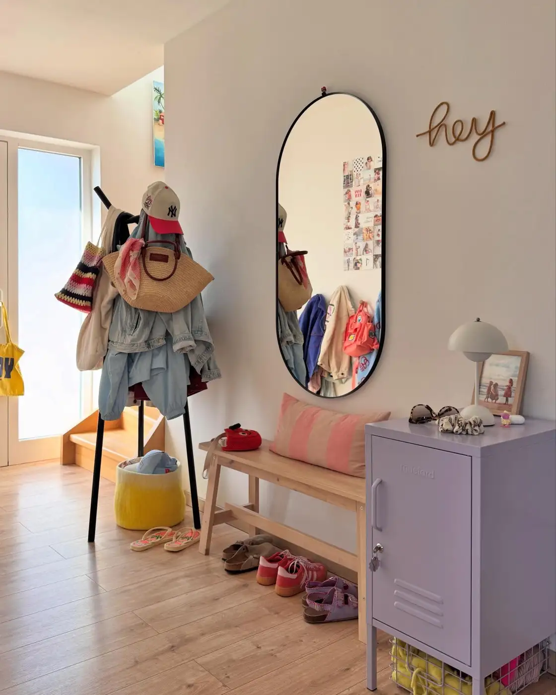 Small entryway with tall cabinet, wooden bench, coat stand, shoe storage, and full-length mirror