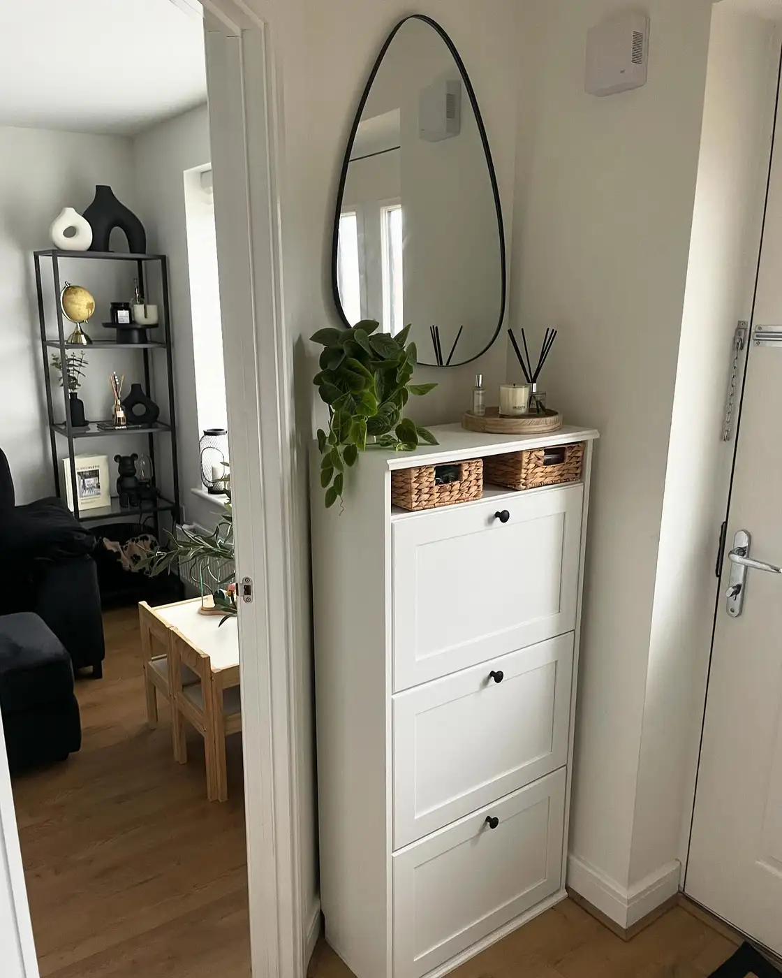 Tall narrow shoe cabinet with woven baskets, oval mirror, and small entryway drop zone