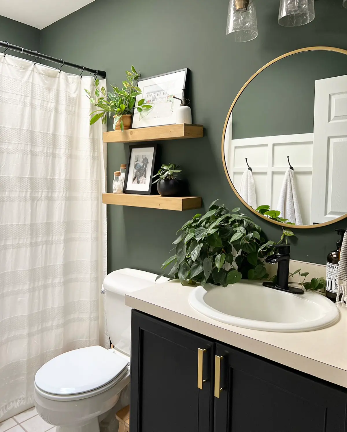 Mint green subway tiled bathroom with brass shower, wall-mounted sink, built-in shelves, plants and checkerboard floor