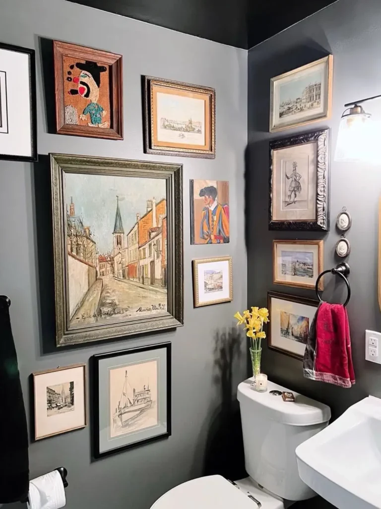 Dark gray bathroom with a salon style gallery wall featuring city scenes, portraits, sketches, and mixed vintage frames.