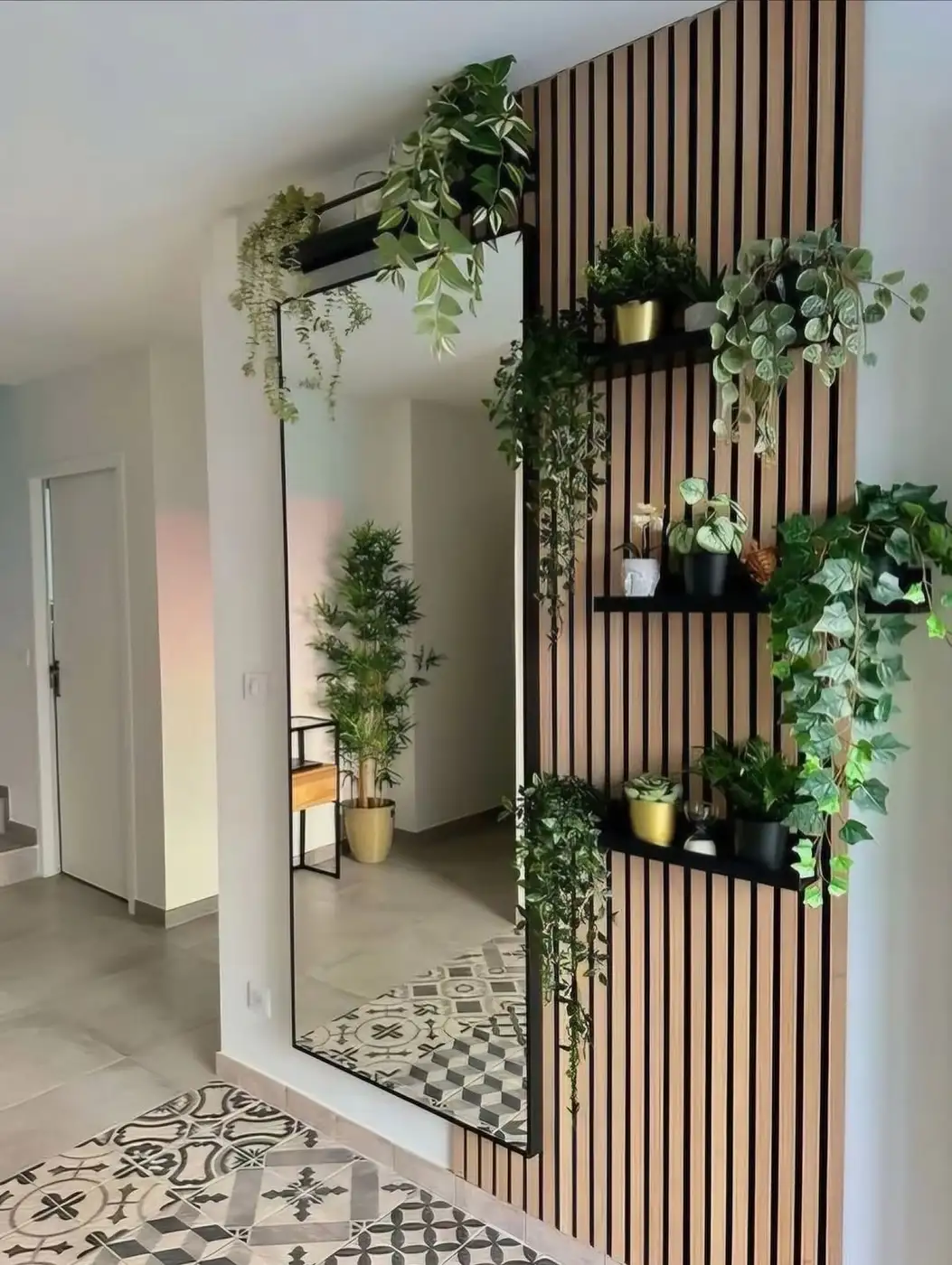 Wood slat entryway wall with narrow floating shelves, greenery, and full-length mirror