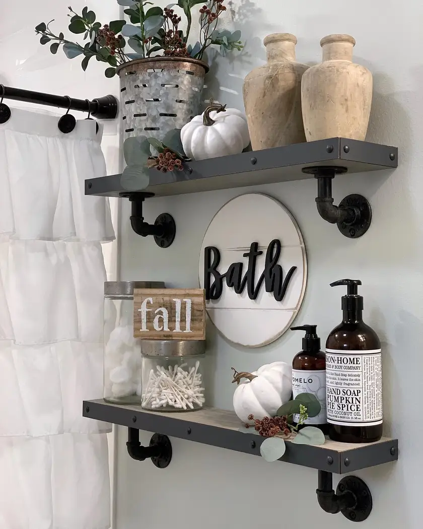 Farmhouse bathroom wall with industrial pipe shelves, glass jars, rustic wood boards, greenery, pottery, and seasonal decor
