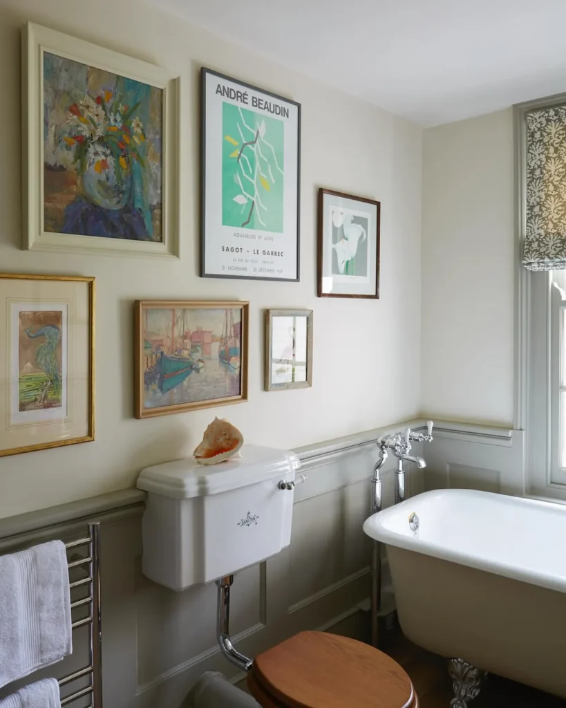 Collected bathroom gallery wall with large and small floral, abstract, harbor, and scenic artwork in mixed frames.