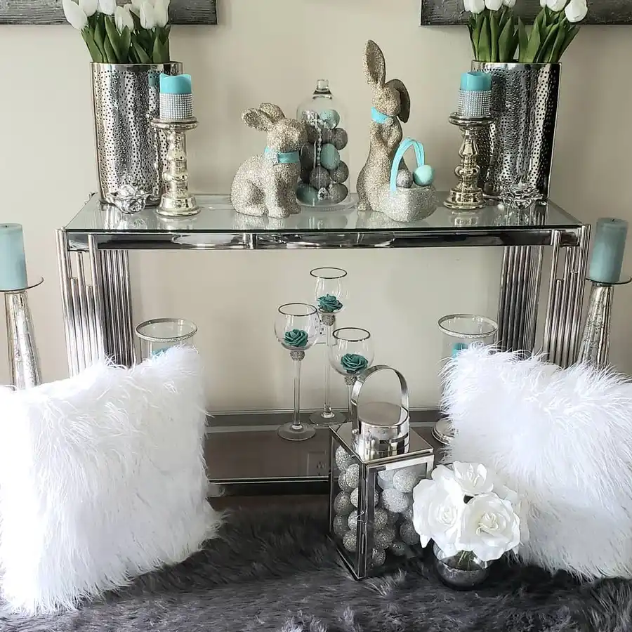 Mirrored entryway console decorated with silver vases, white tulips, bunny figurines, candles, aqua accents, and glass accessories.