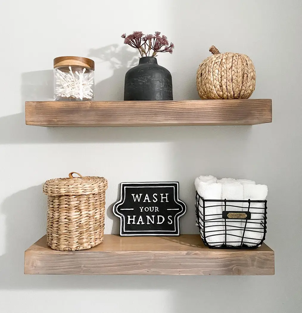 Modern farmhouse floating wood shelves styled with woven baskets, white towels, glass jars, black accents, and simple decor