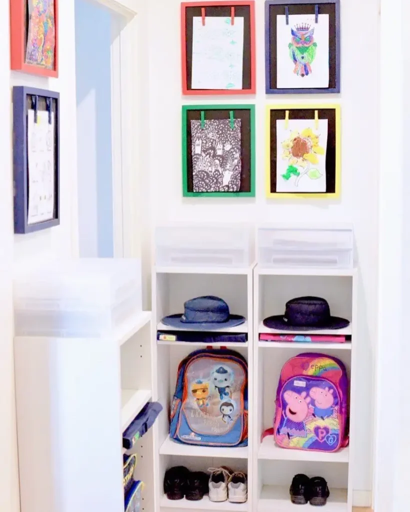 Children’s backpack cubbies with shoe storage and colorful framed artwork displayed above each section.