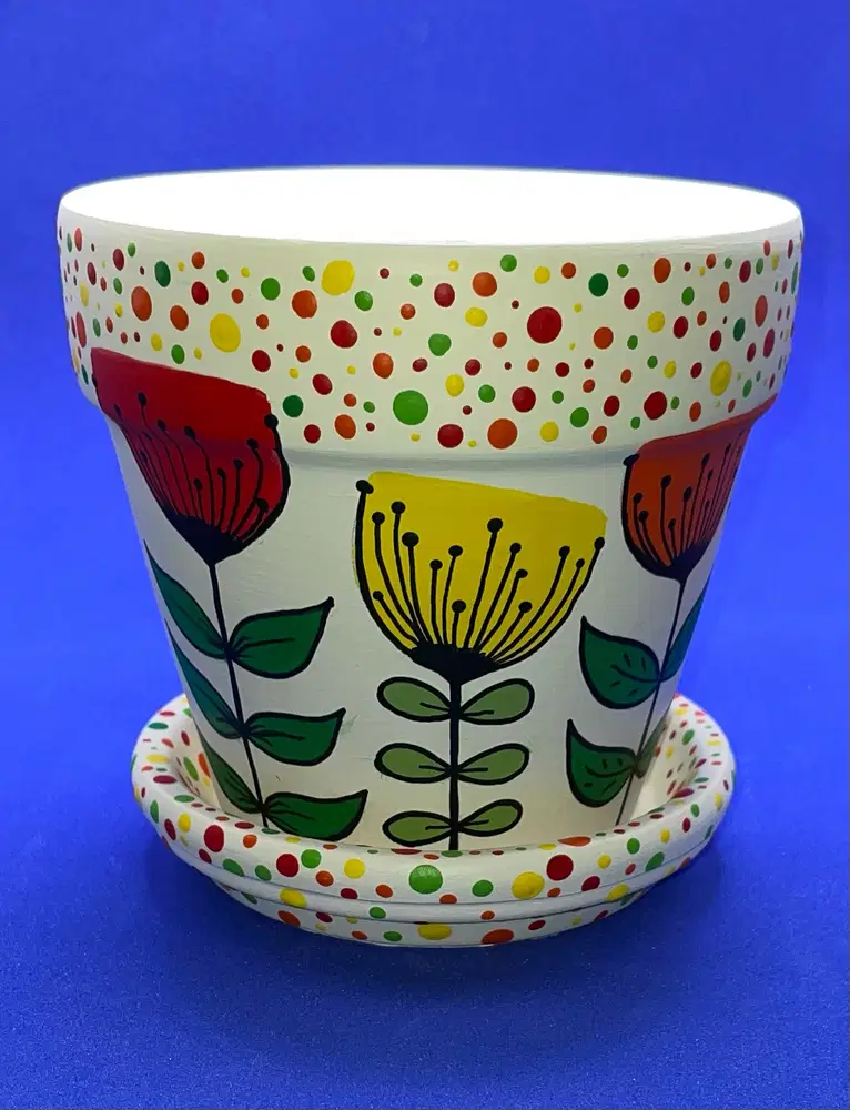 White flower pot painted with oversized colorful flowers and multicolor polka dot borders