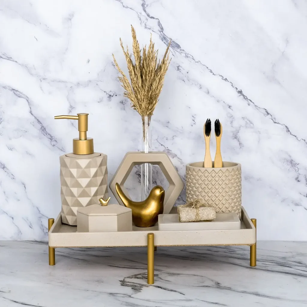 Raised beige tray with gold feet, geometric soap dispenser, toothbrush cup, soap dish and gold bird decorations.