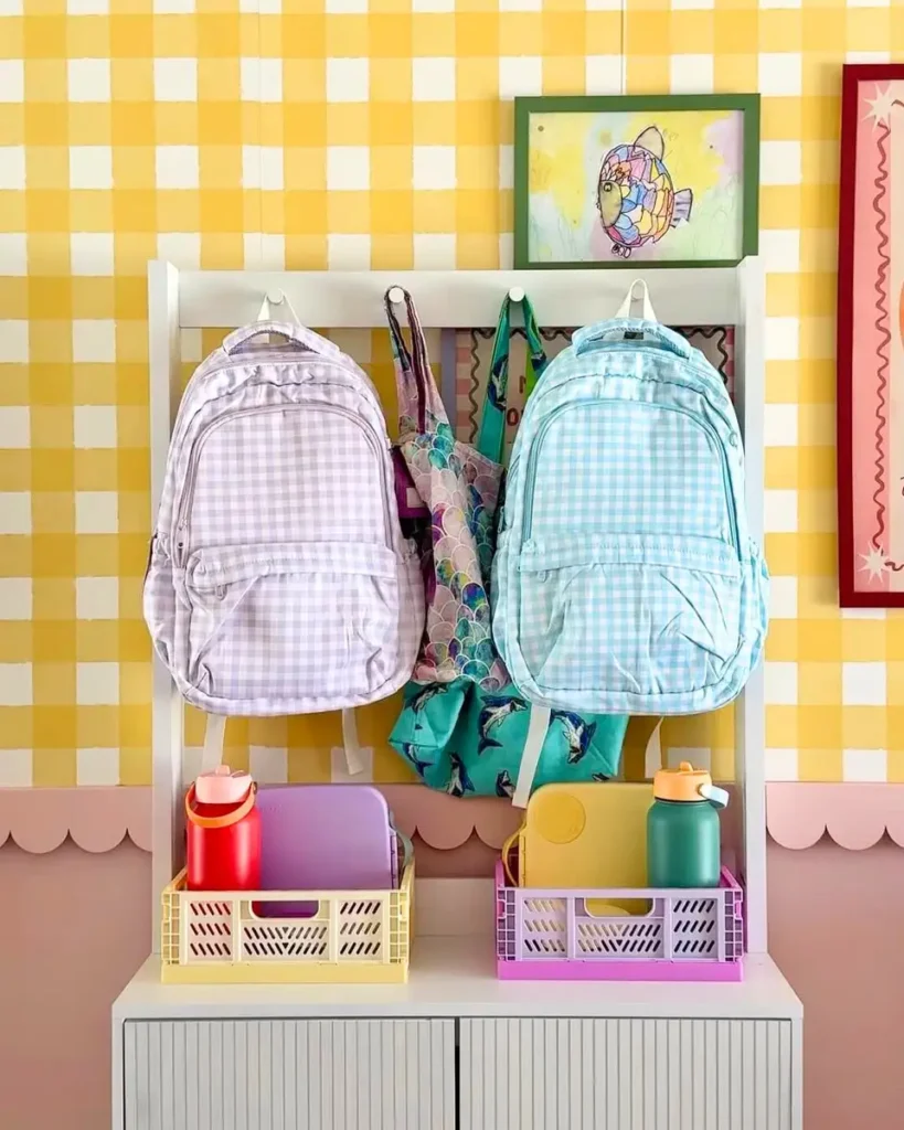 Colorful school drop zone with backpacks on hooks and crates holding lunchboxes and water bottles below.