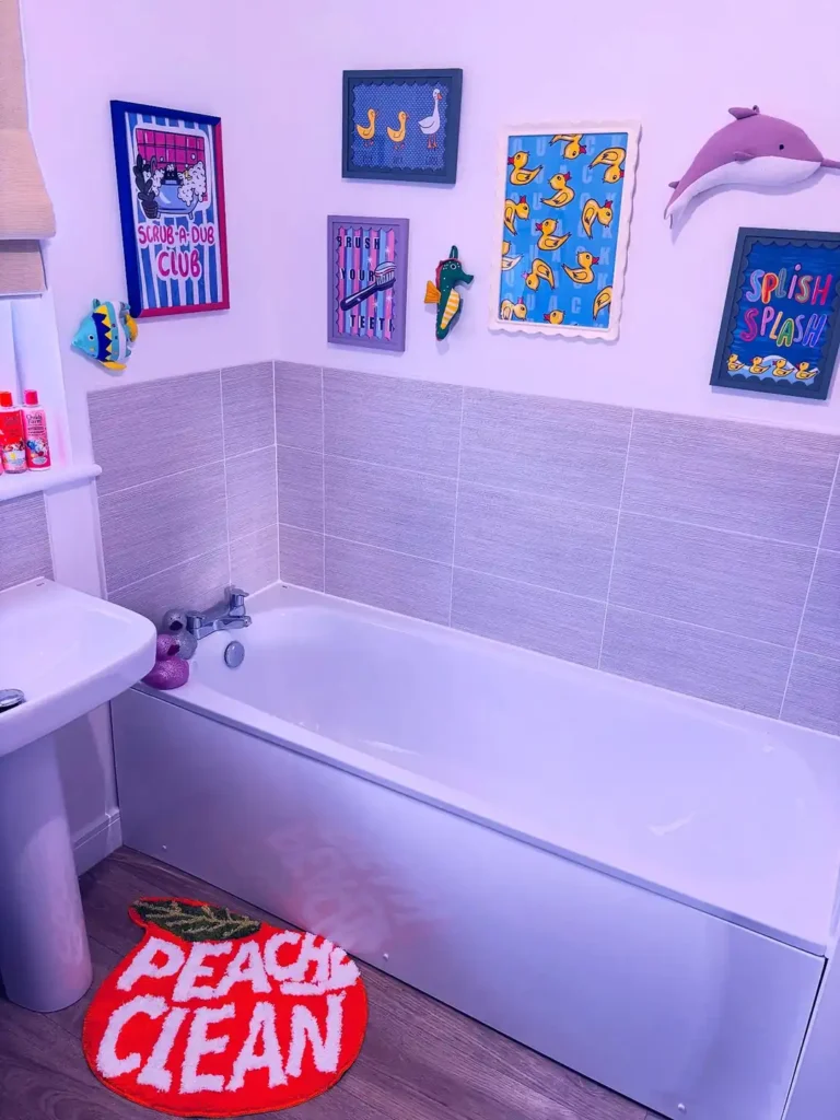 Playful bathroom gallery wall with colorful duck prints, bath themed artwork, fish decor, and a dolphin wall accent.