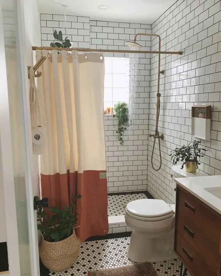 Small bathroom with horizontal white subway tiles, a high shower curtain, brass fixtures, and penny tile flooring.