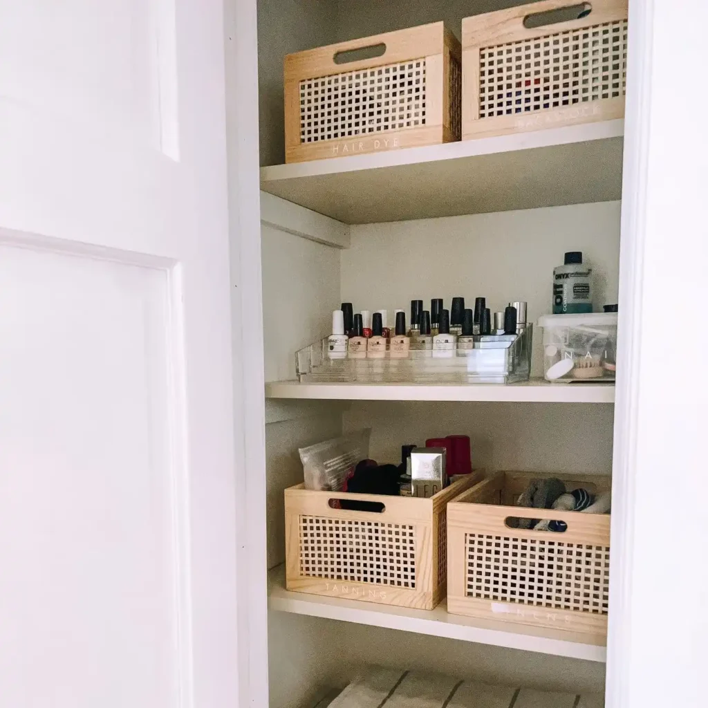 Bathroom closet shelves with woven baskets, clear trays, and organized beauty, skincare, and personal care products.