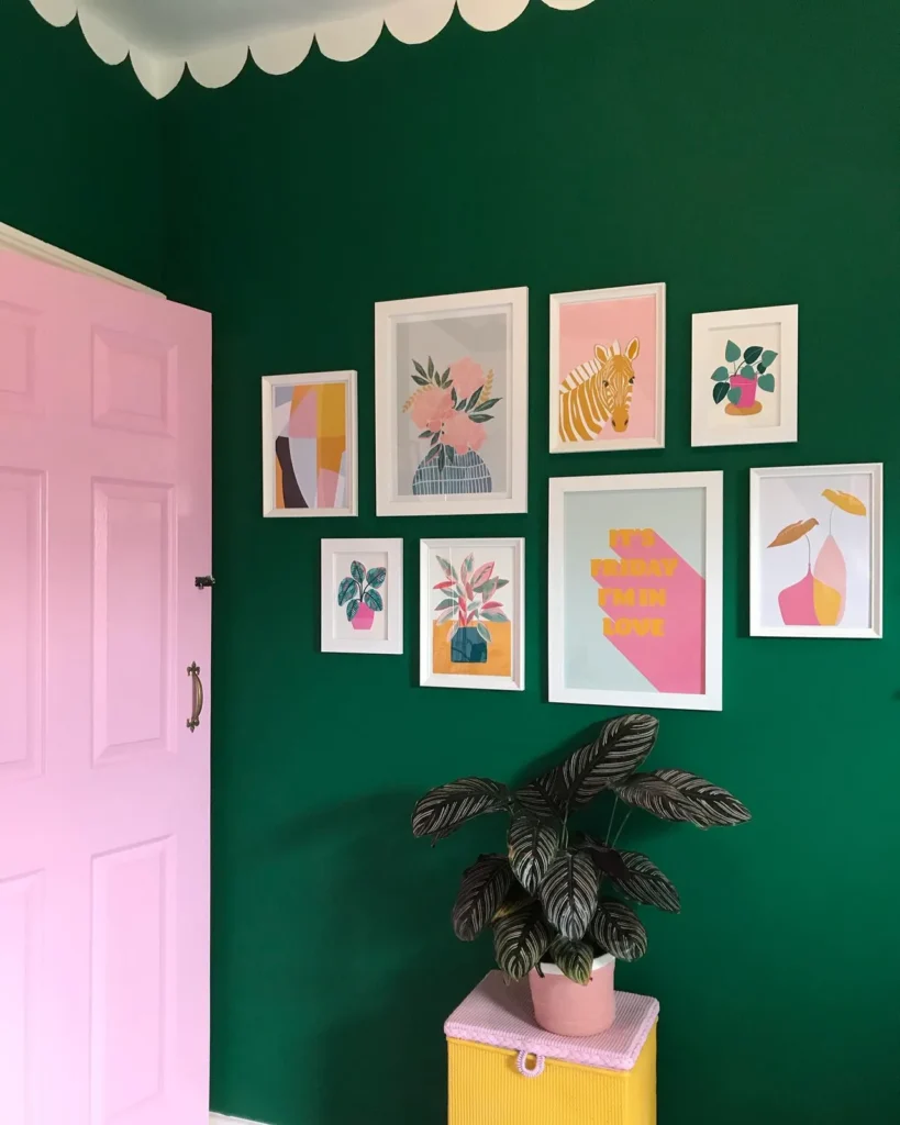 Colorful bathroom gallery wall with pastel botanical, zebra, floral, and graphic prints in white frames on a dark green wall.