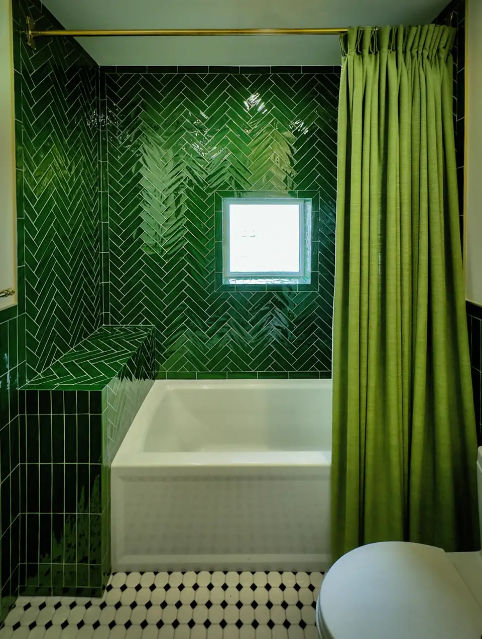 Bold bathroom with dark green subway tiled shower, tropical wallpaper, pink paneling, patterned floor and brass accents