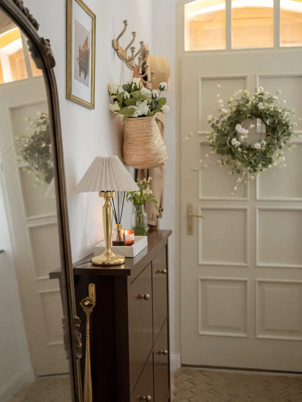 Slim dark entryway cabinet with wall hooks, small lamp, tray, and full-length mirror