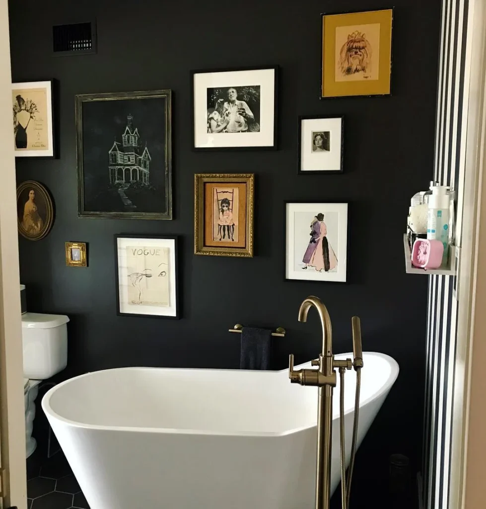 Moody black bathroom gallery wall with vintage portraits, fashion sketches, photography, and mixed framed artwork above a white tub.
