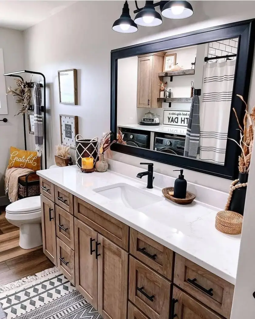 Modern farmhouse vanity with warm wood cabinetry, oversized black mirror, black faucet and hardware, white countertop, and patterned runner