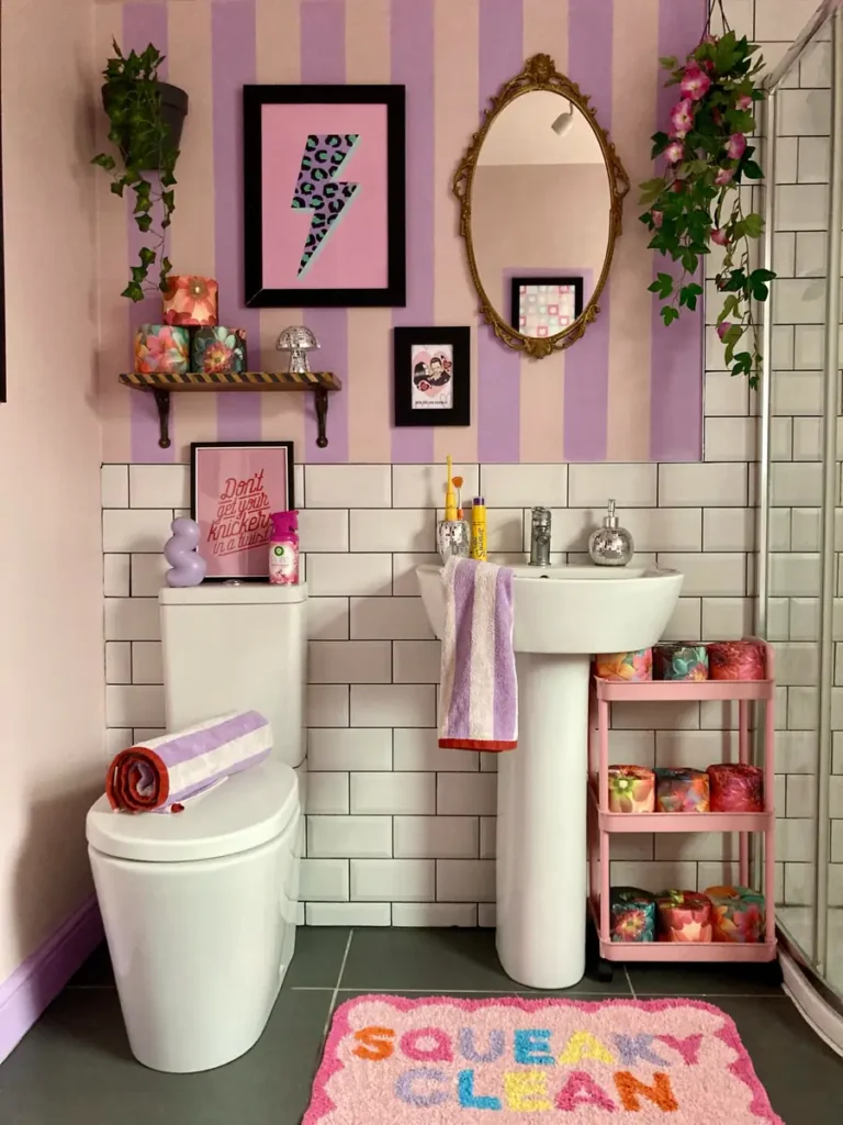 Small powder room with a tropical jungle mural above dark green subway tiles and warm herringbone wood flooring.