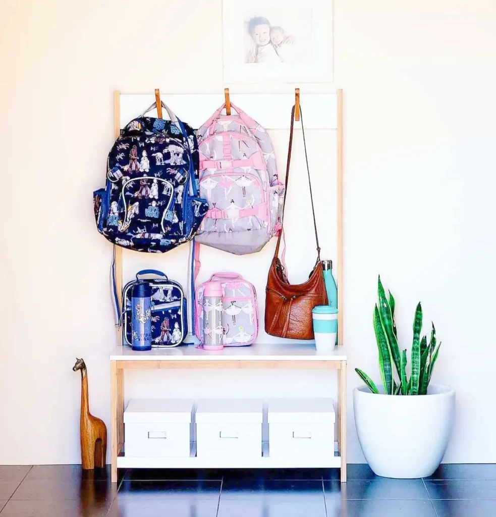 Compact grab-and-go school station with backpacks, lunch bags, water bottles, bench, and lower storage boxes.