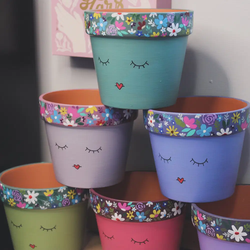 Pastel flower pots with colorful floral painted rims, sleepy eyes, and tiny heart shaped mouths