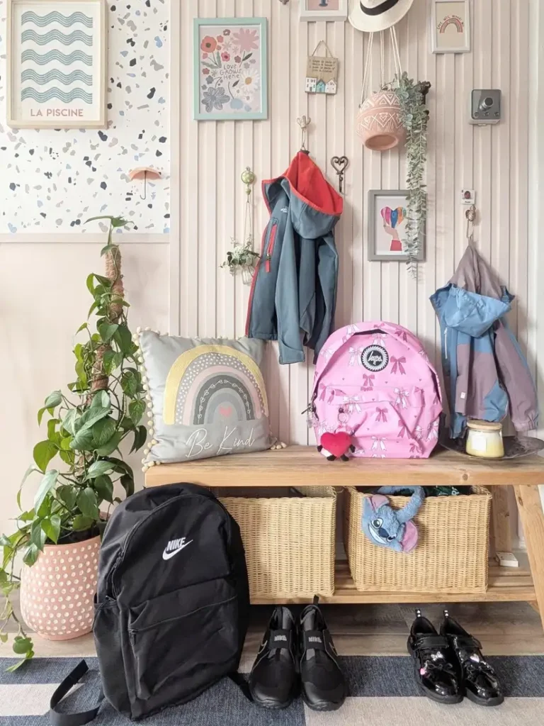 Family entryway bench with wall hooks, backpacks, jackets, woven baskets, and shoes organized underneath.