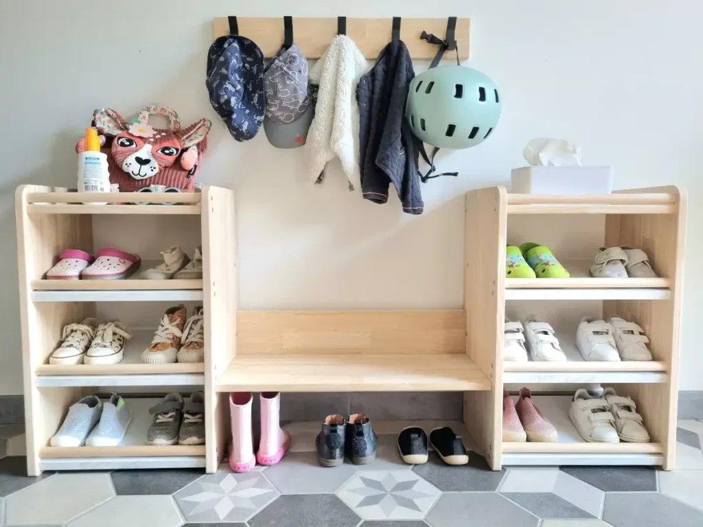 Wooden entryway shoe racks with central bench and wall hooks holding hats, jackets, and a helmet.