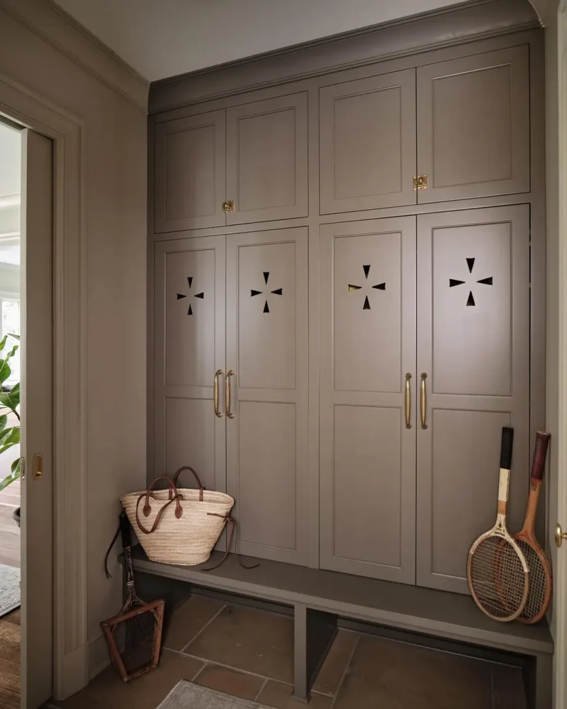 Floor-to-ceiling taupe lockers with decorative vent cutouts and a matching built-in bench.