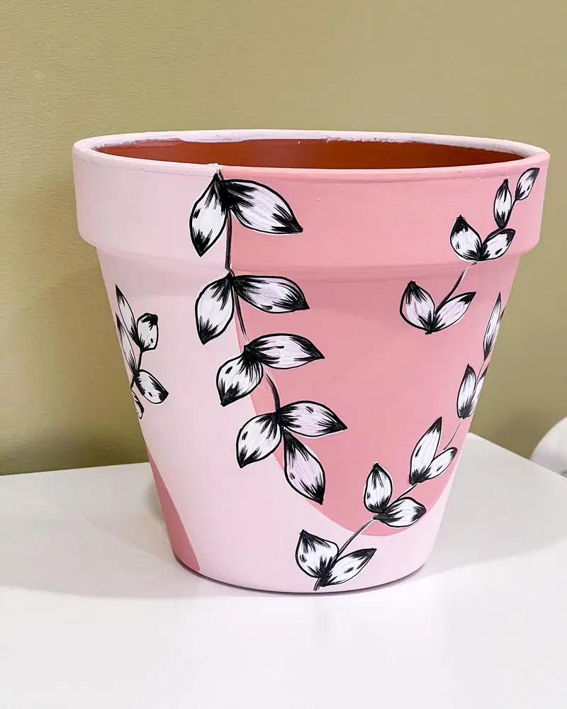 Soft pink flower pot painted with black and white leafy vines and curved botanical branches