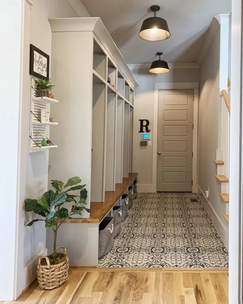 Long hallway drop zone with built-in cubbies, a wooden bench, fabric bins, and patterned floor tiles.