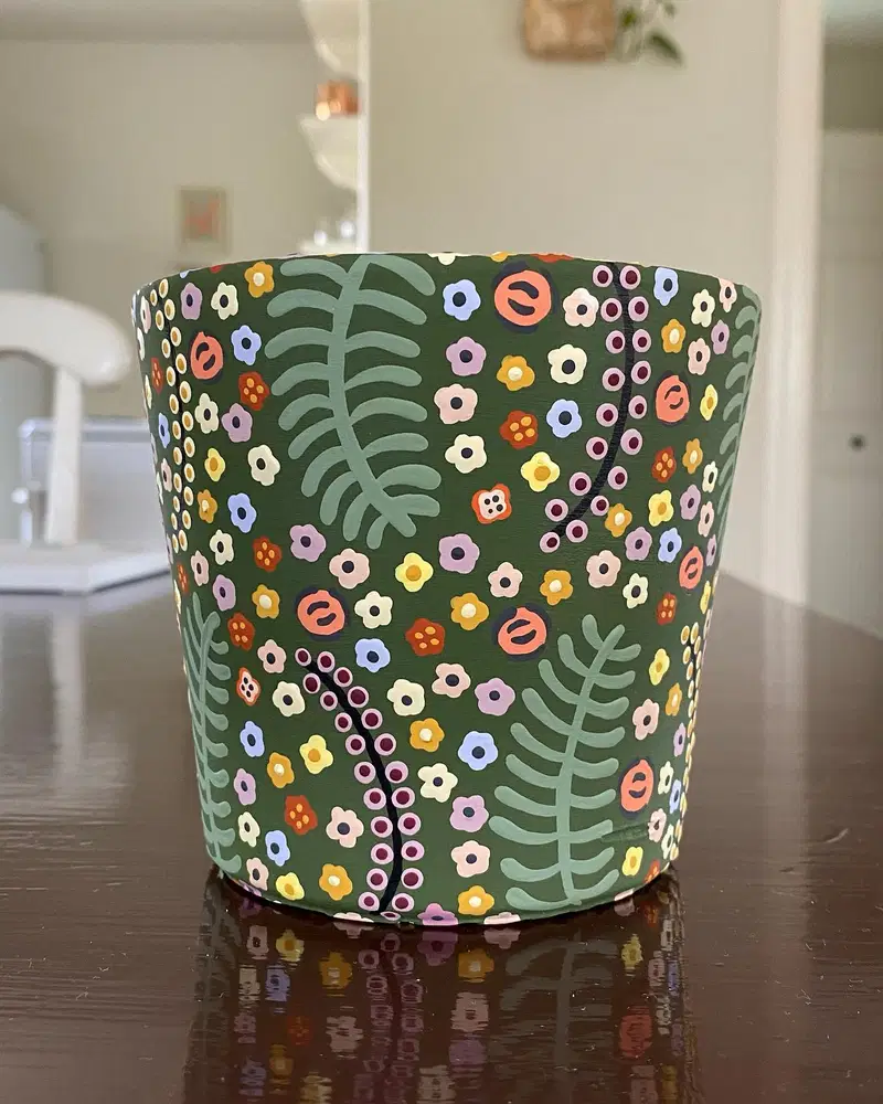 Dark green flower pot covered with tiny colorful blooms, sage fronds, and dotted stems