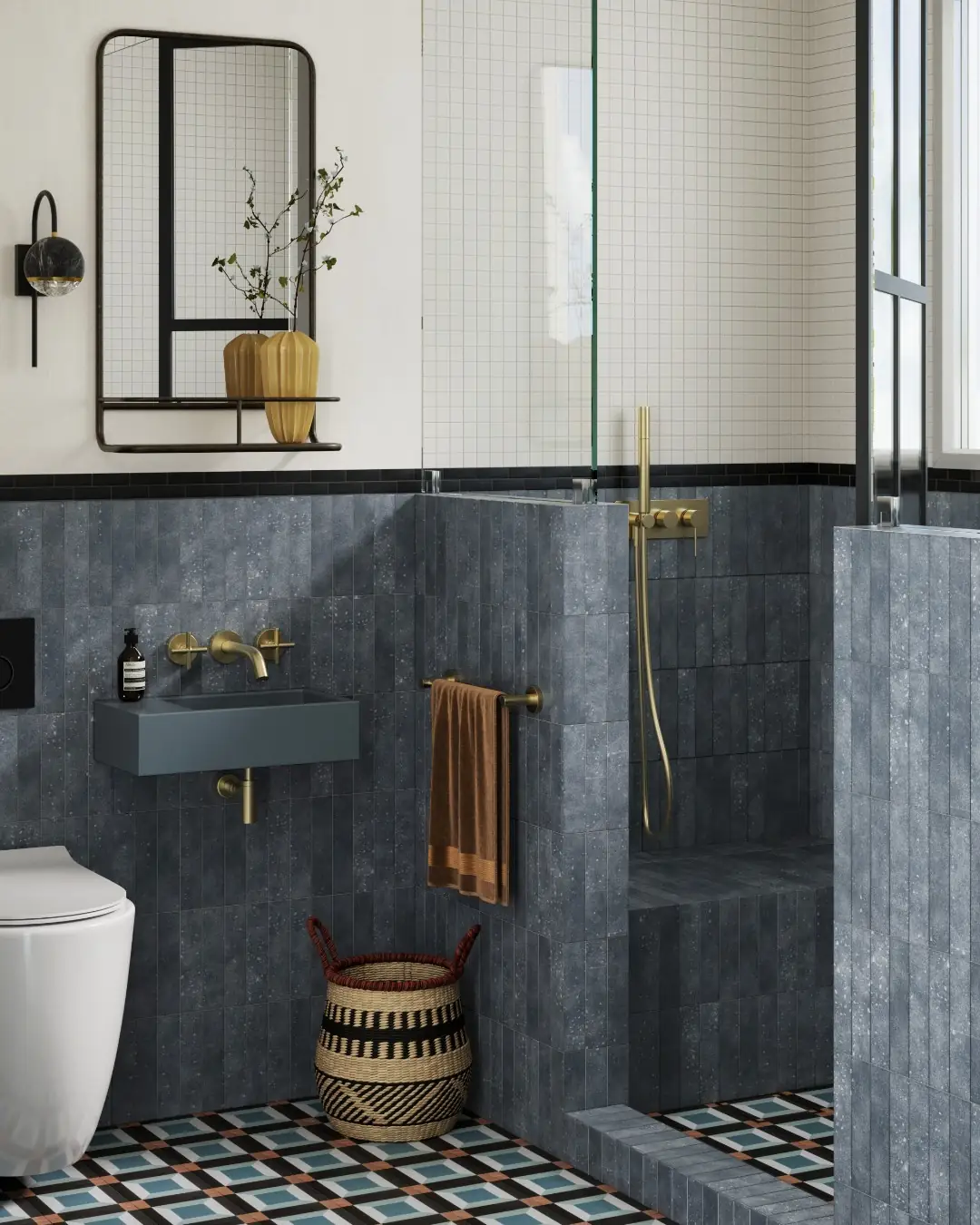 Modern guest bathroom with blue-gray tile, brass fixtures, patterned floor, wall-mounted sink and glass shower enclosure