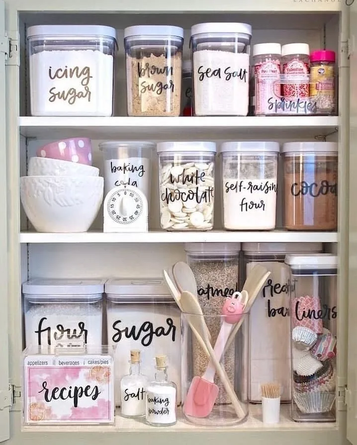 Clear pantry canisters filled with flour, sugar, oats, cocoa, and baking staples arranged neatly on deep shelves