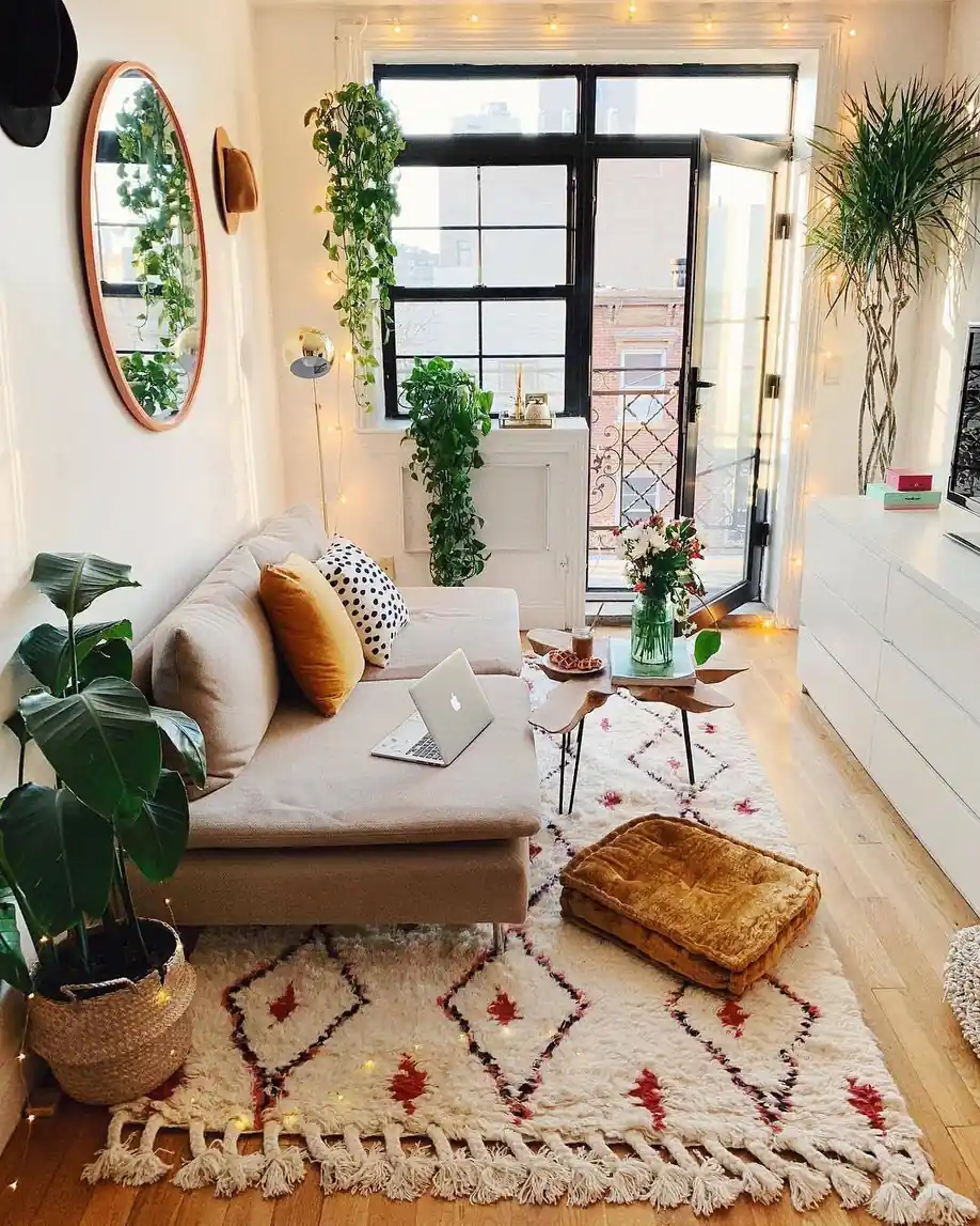 Narrow living room with a long sofa, floral window shades, coffee table, and bright window at the far end