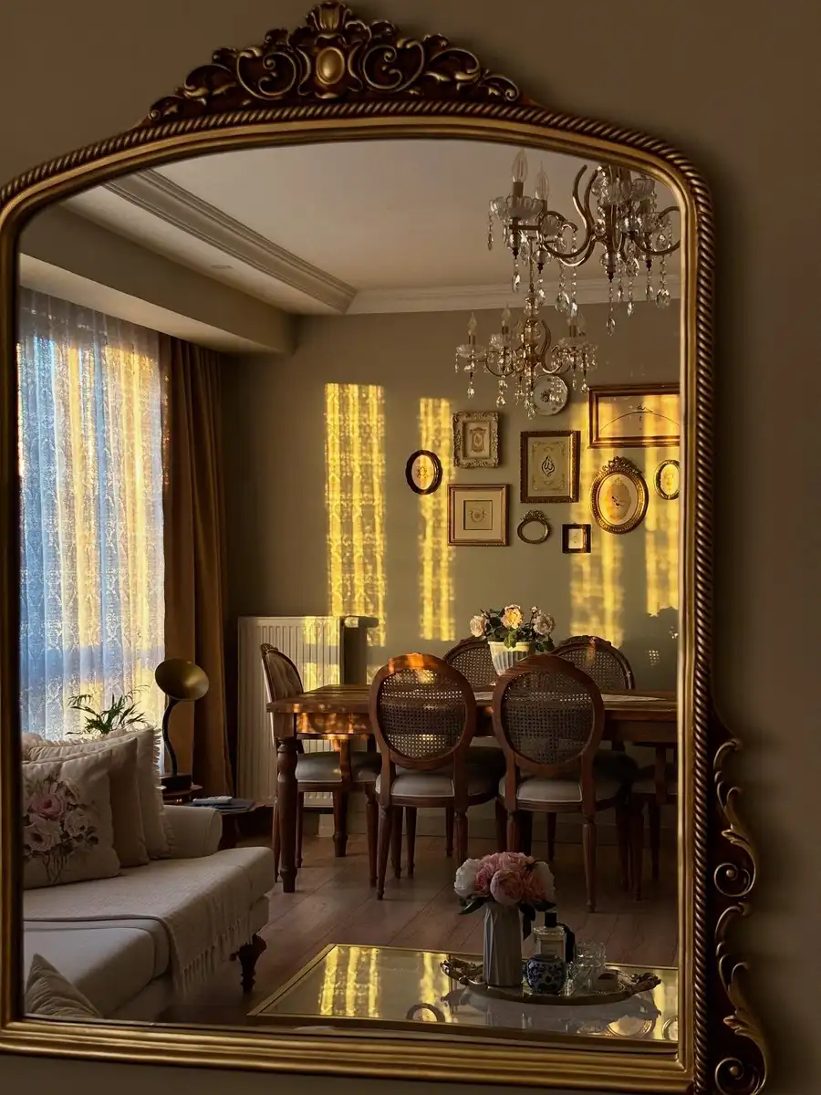 Large ornate vintage mirror reflecting a dining room with cane chairs and chandelier