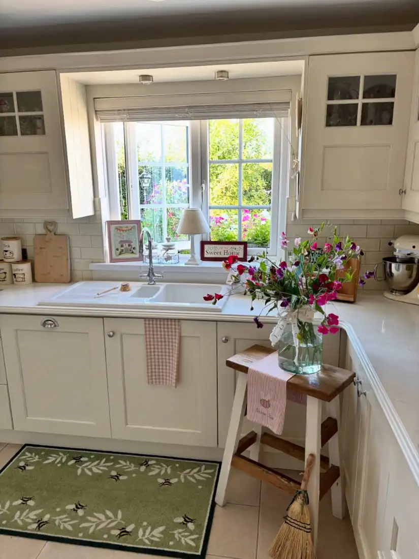 Kitchen window sill styled with a small lamp, framed art, and simple decorative sign