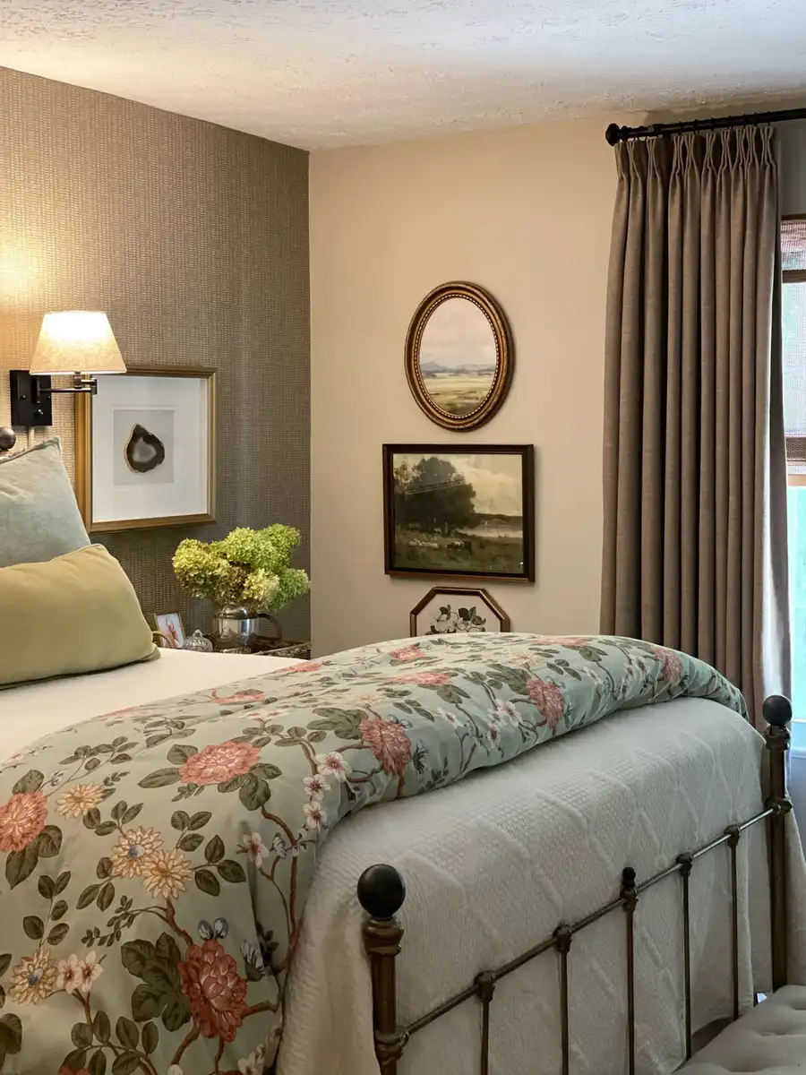 Vintage bedroom with floral coverlet, dark metal bed frame, white bedding, and small framed art