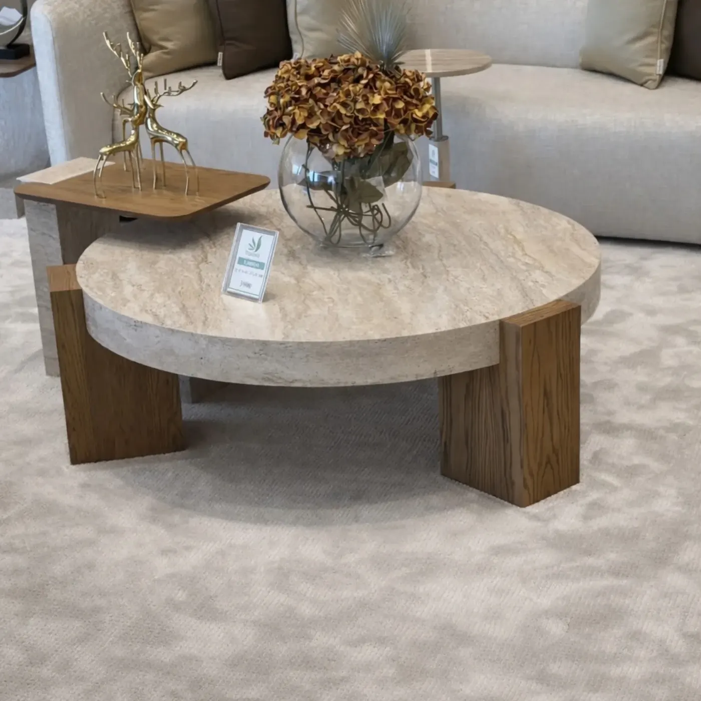 Round wooden coffee table with a simple glass vase filled with brown dried flowers