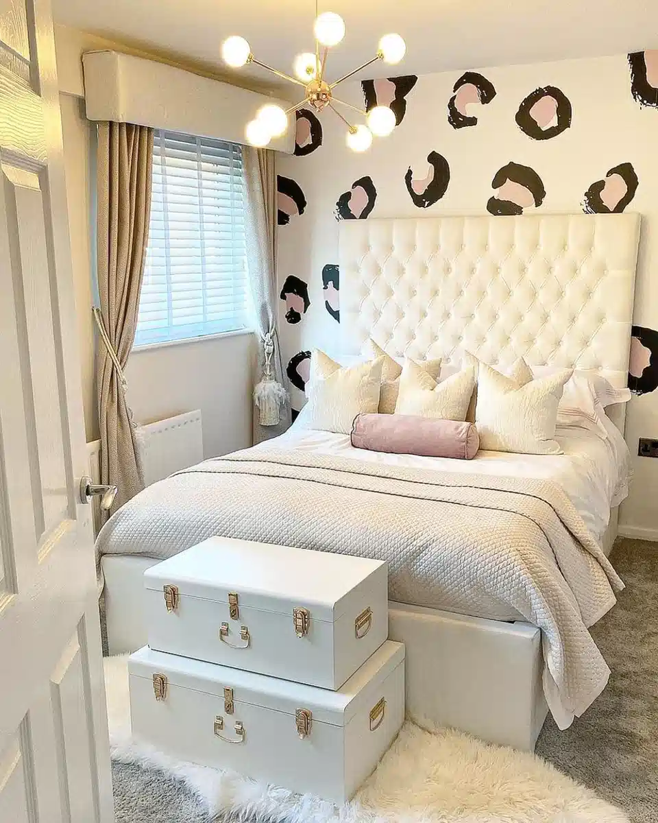 Bedroom with oversized leopard spots painted on the wall behind a cream tufted bed