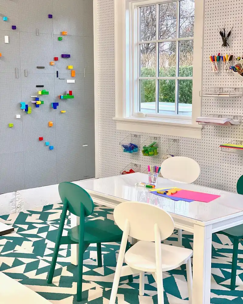 Kids homework table surrounded by pegboard storage, clear bins, paper trays, and colorful supplies