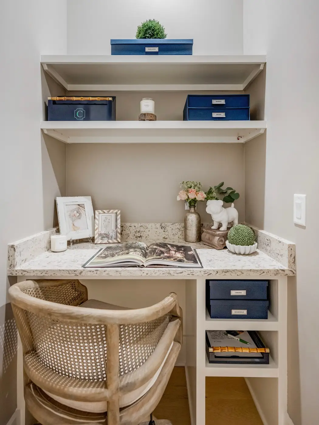 Compact homework desk built into a narrow wall niche with overhead shelves and storage cubbies