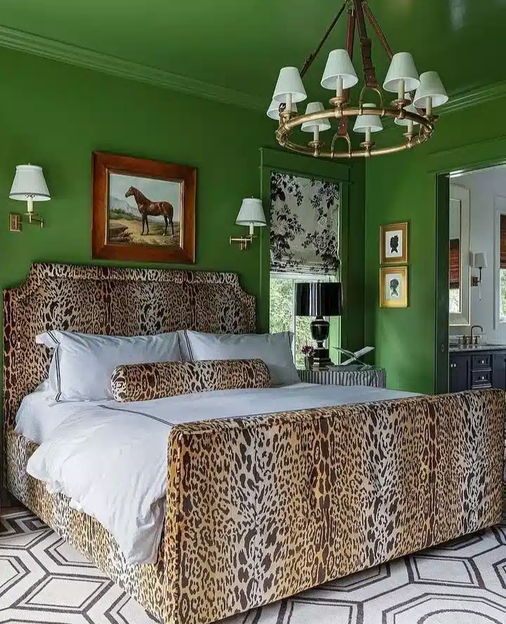 Leopard print upholstered bed with white bedding against deep green bedroom walls
