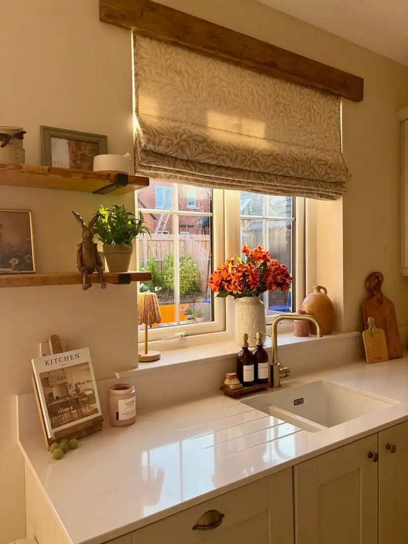 Deep kitchen window sill with a large vase of orange flowers and simple decorative vessels