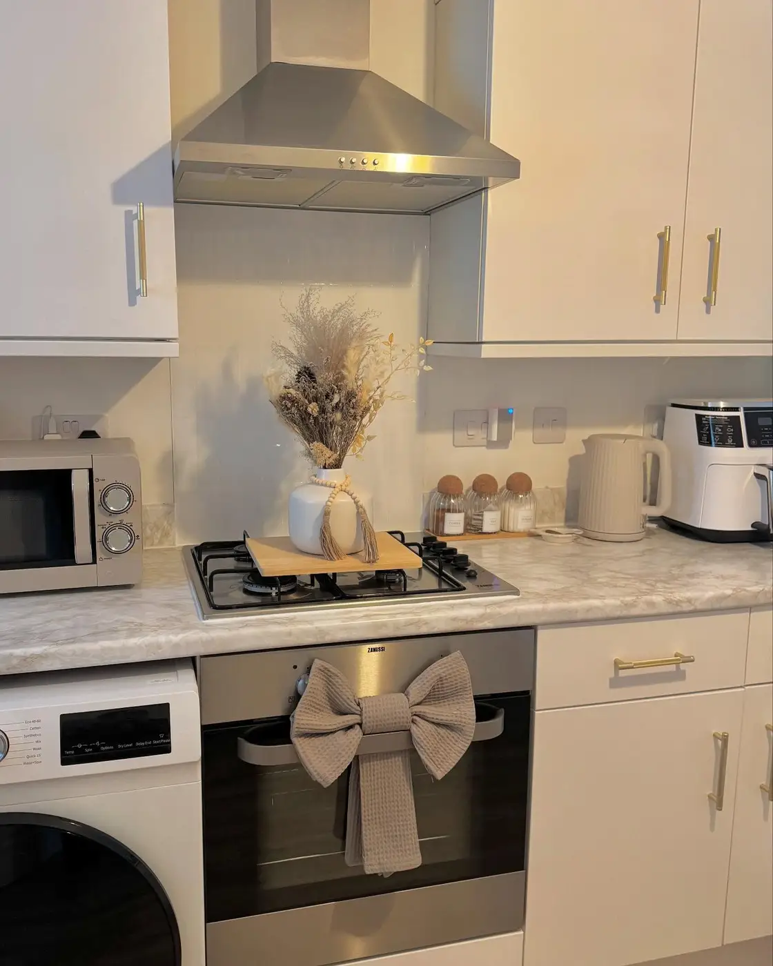 White kitchen counter with dried floral arrangement in a vase displayed on a removable wooden board