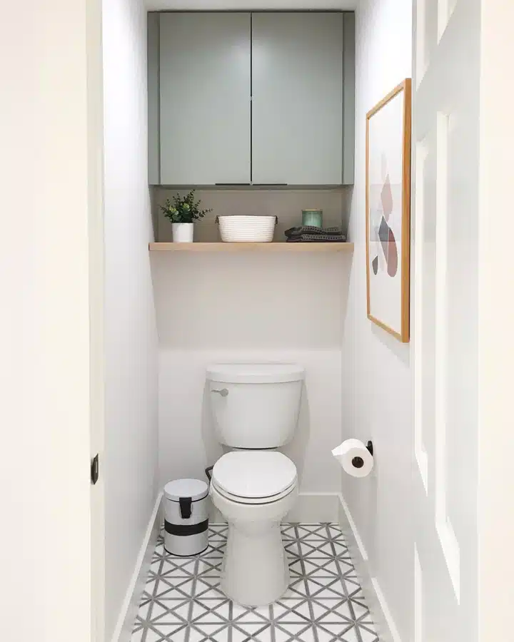 05 White wall cabinets above a toilet with a narrow wooden shelf and small storage basket