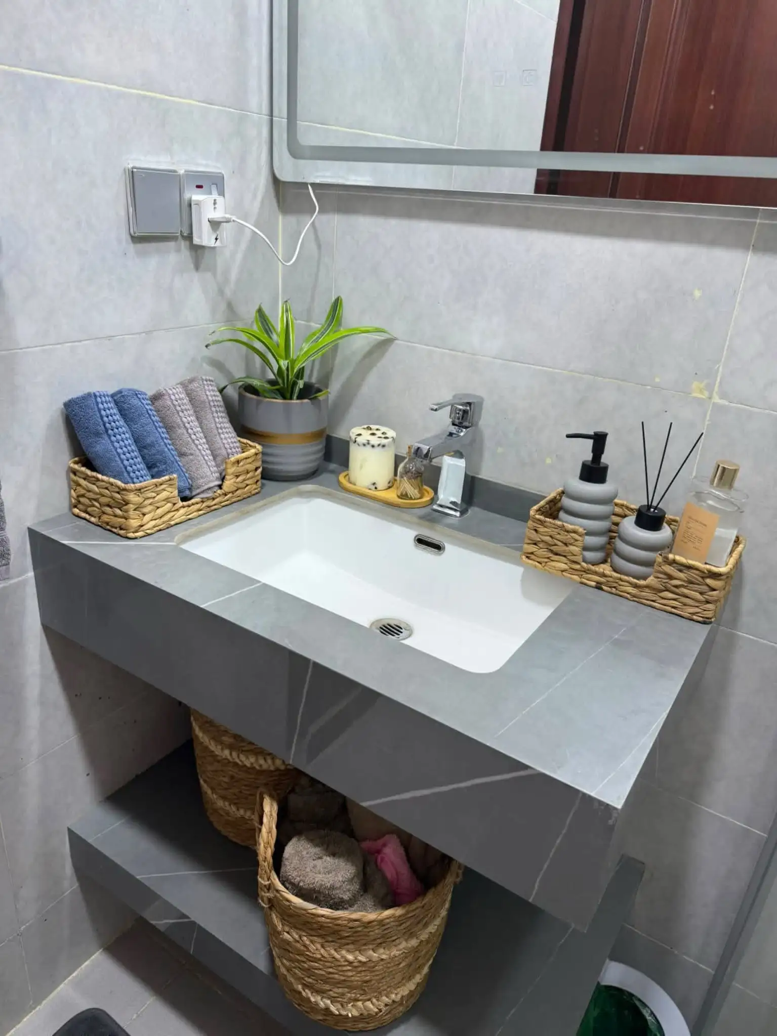 Open bathroom vanity shelf with two woven baskets storing towels and bathroom essentials beneath the sink
