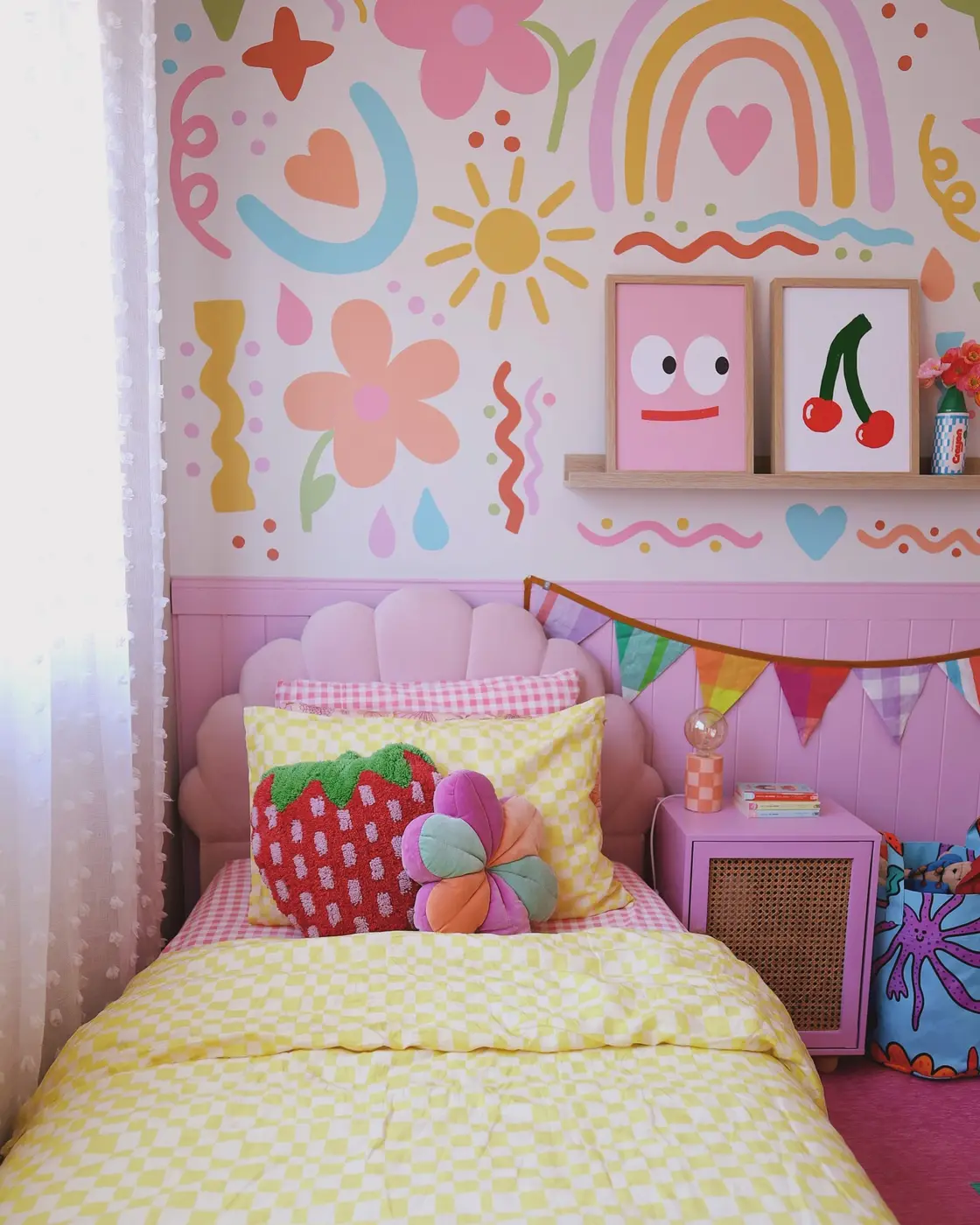 Colorful girls bedroom with pink wall paneling, oversized flowers, rainbows, hearts, and bright bedding