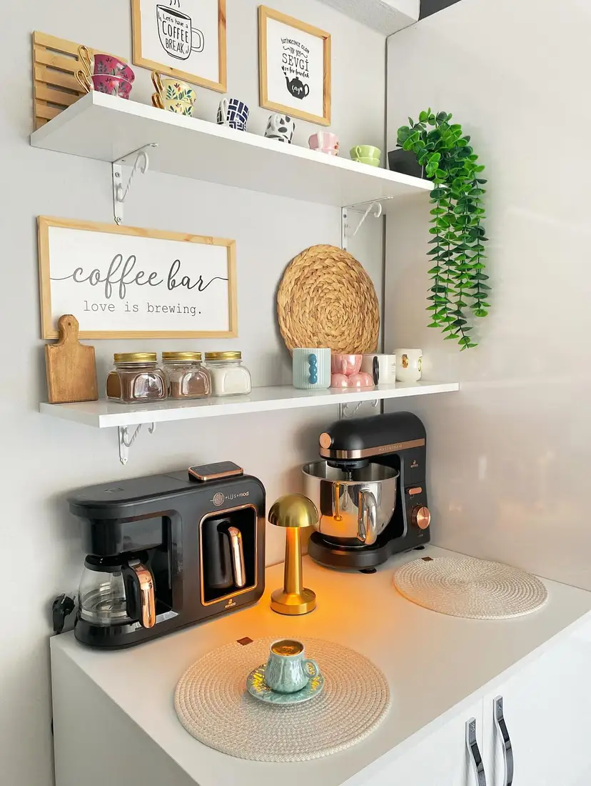 Modern coffee station with black appliances, white shelves, colorful mugs, gold lamp, jars, and trailing greenery