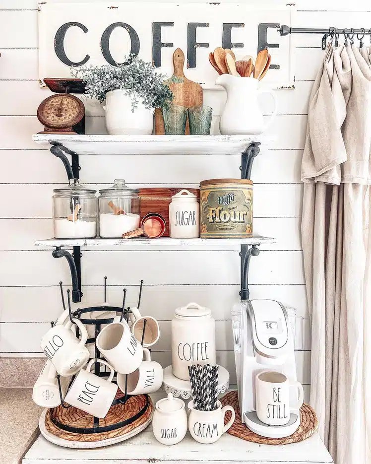 Vintage farmhouse coffee bar with distressed wood shelves, large coffee sign, white pitchers, old-style scale, mug rack, and coffee machine