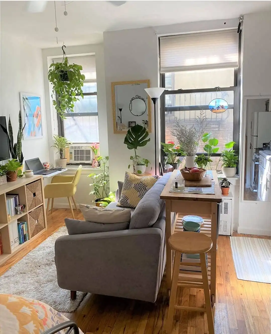 Very narrow living room with wall-side seating, a long yellow rug, small table, and clear center walkway